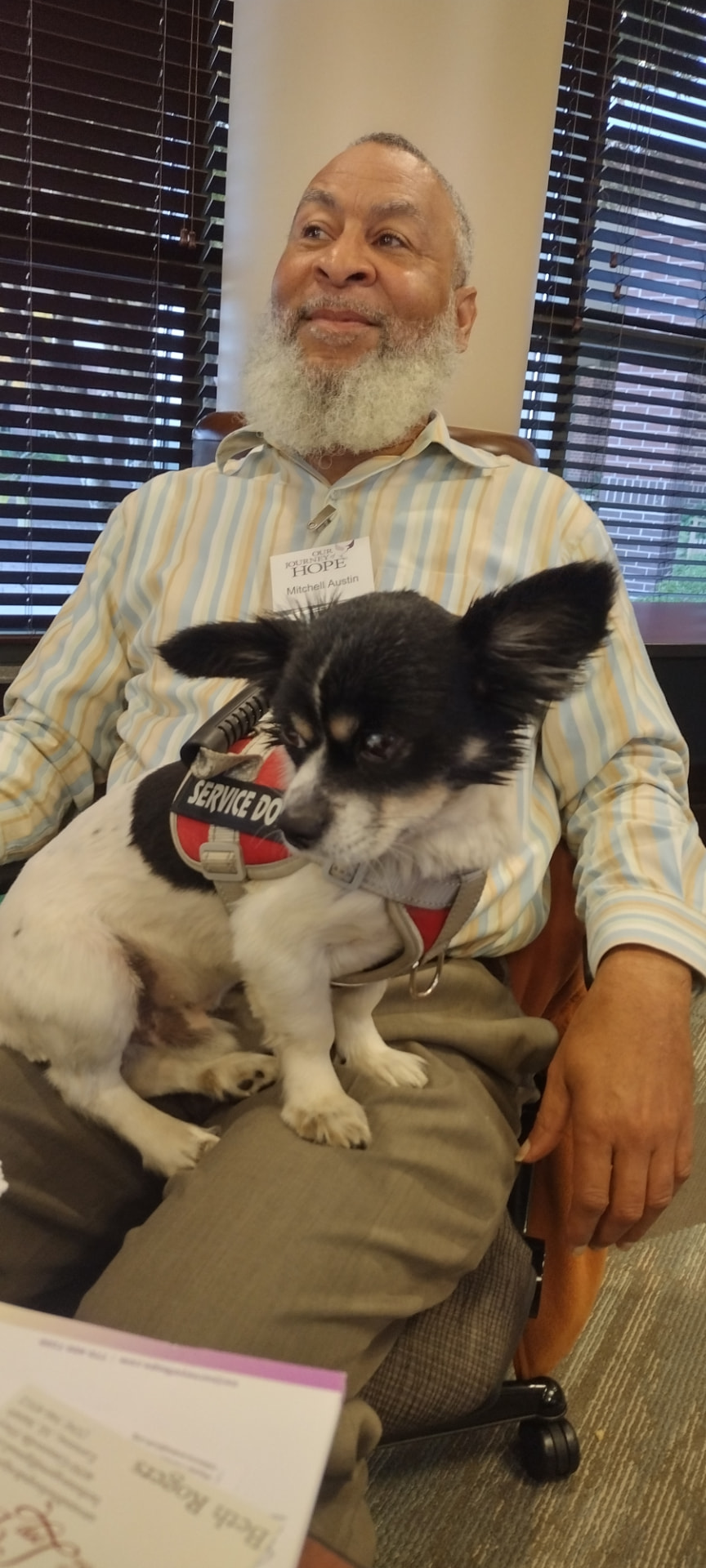 Mitchell Austin, founder of Chosen Vessels, seated with his service dog resting on his lap at a community event